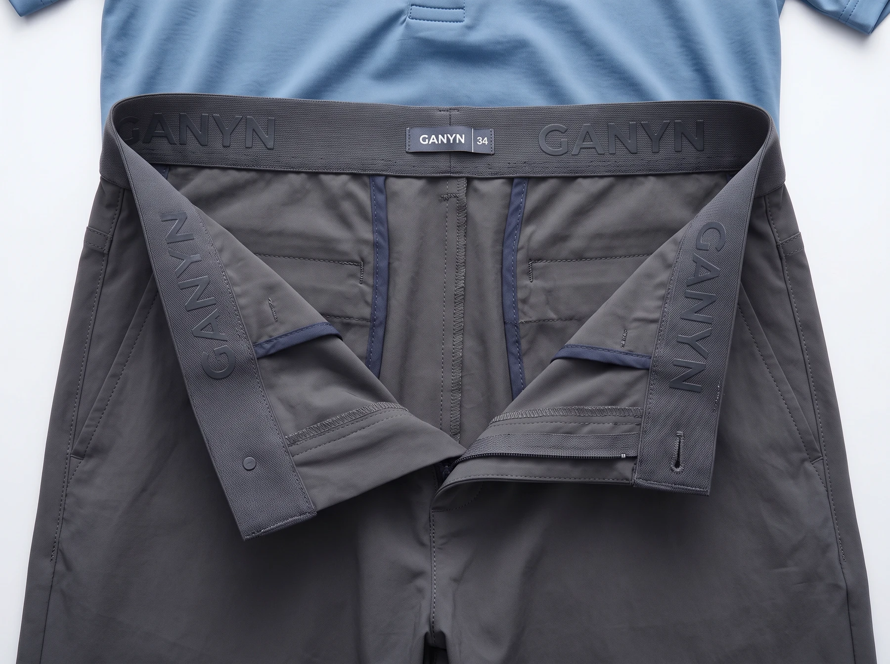 Wide dark grey elastic waistband with tonal GANYN silicone gripper lettering inside lightweight golf trousers