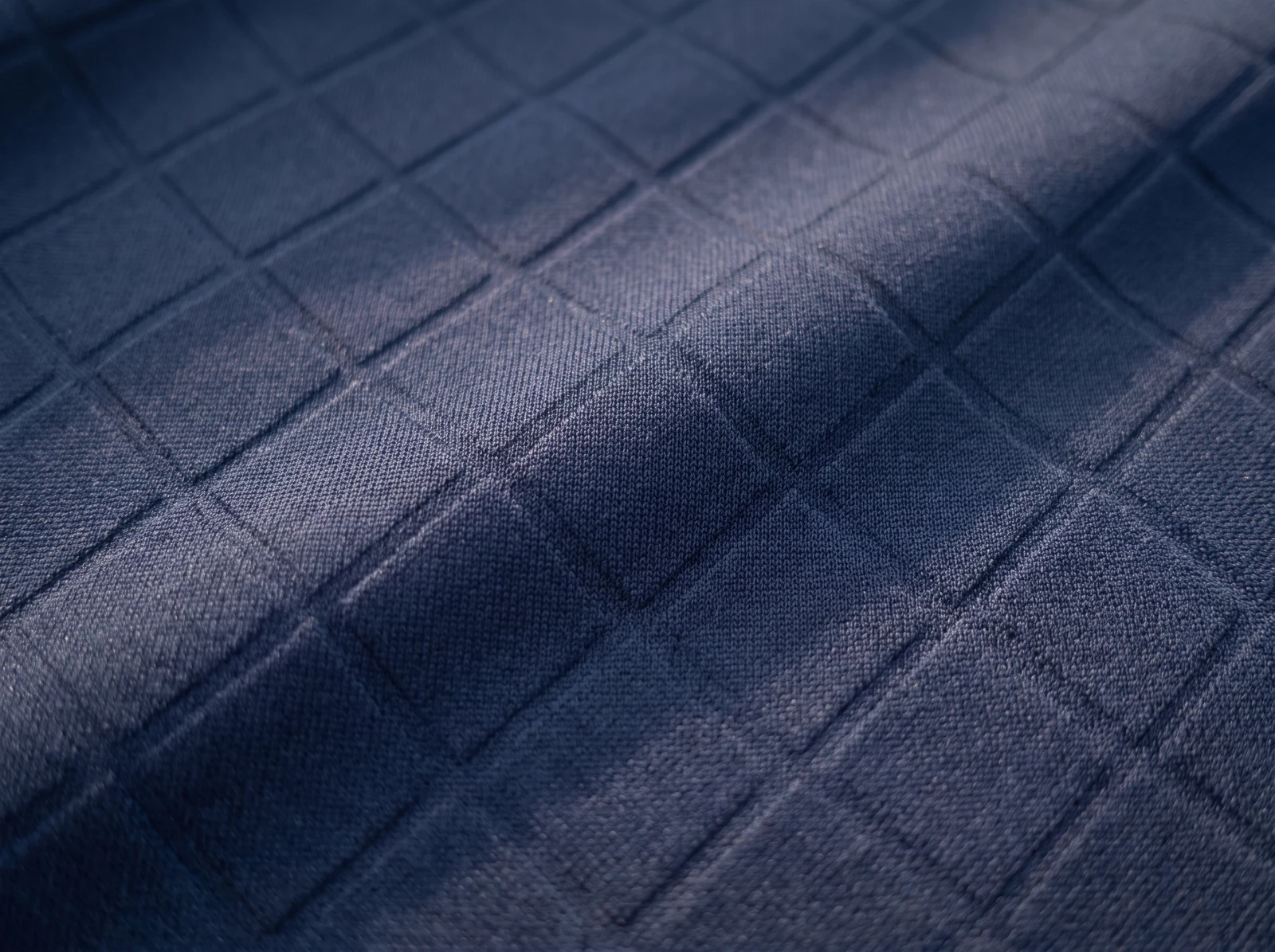Tone-on-tone embossed geometric relief on a navy fabric swatch
