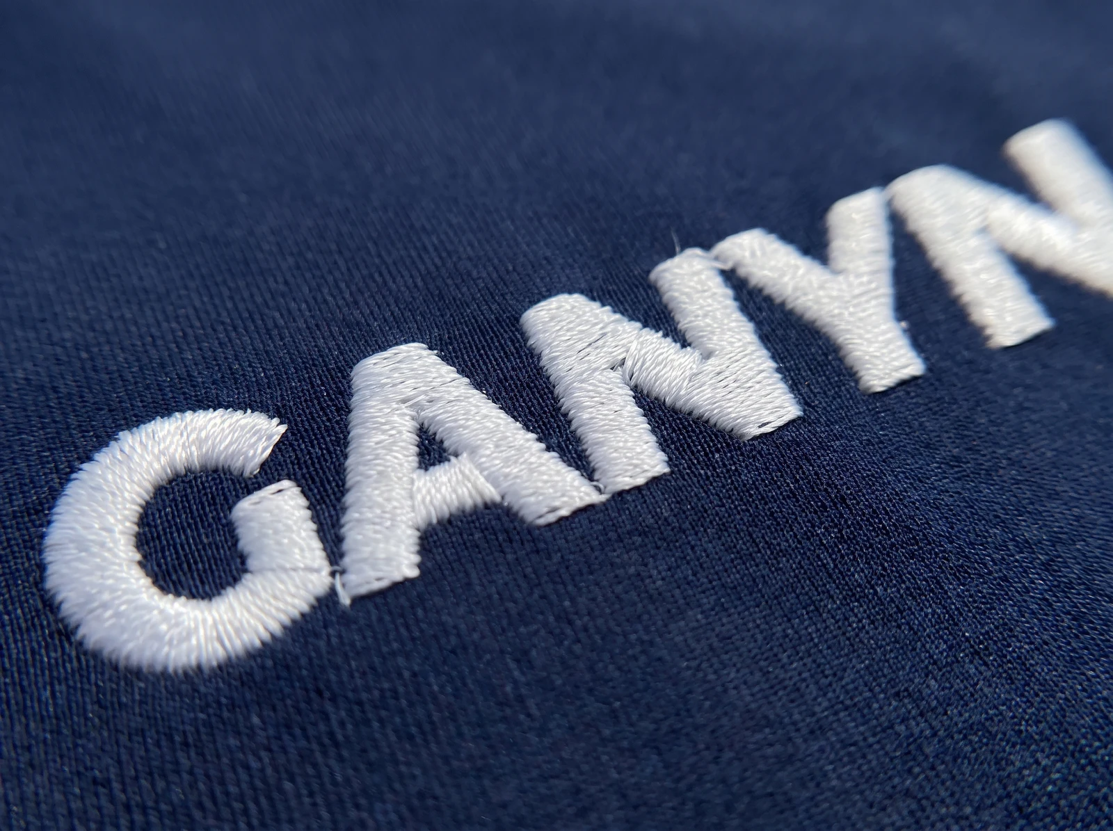 White thread embroidery on navy golf polo fabric