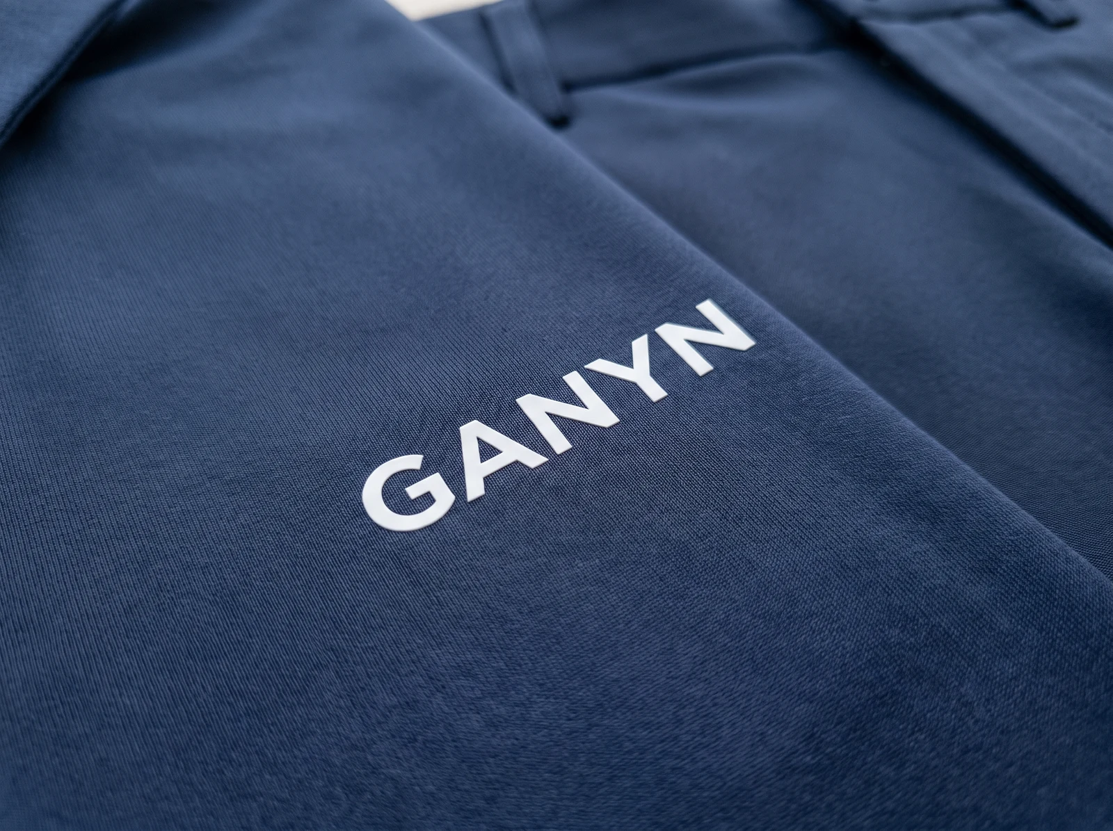 Flat white heat-transfer logo on navy stretch fabric