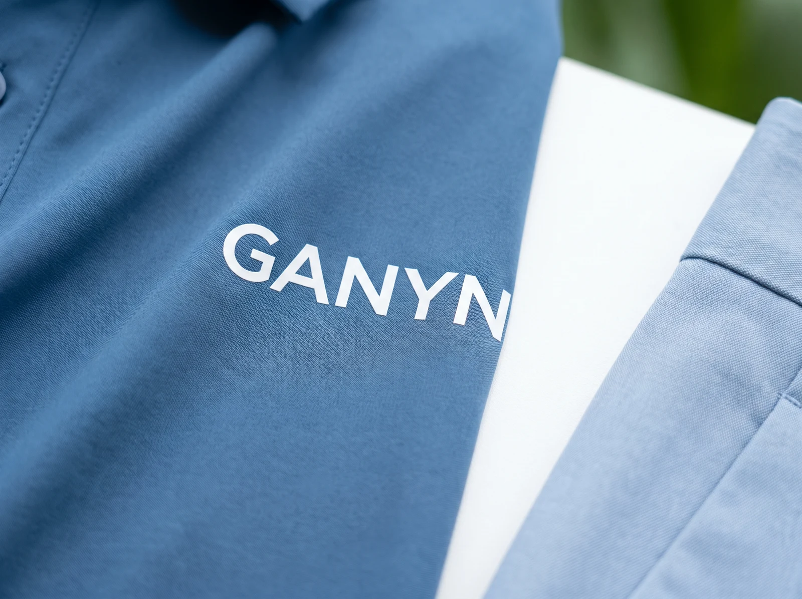 Flat white GANYN screen-printed wordmark on fine blue performance fabric