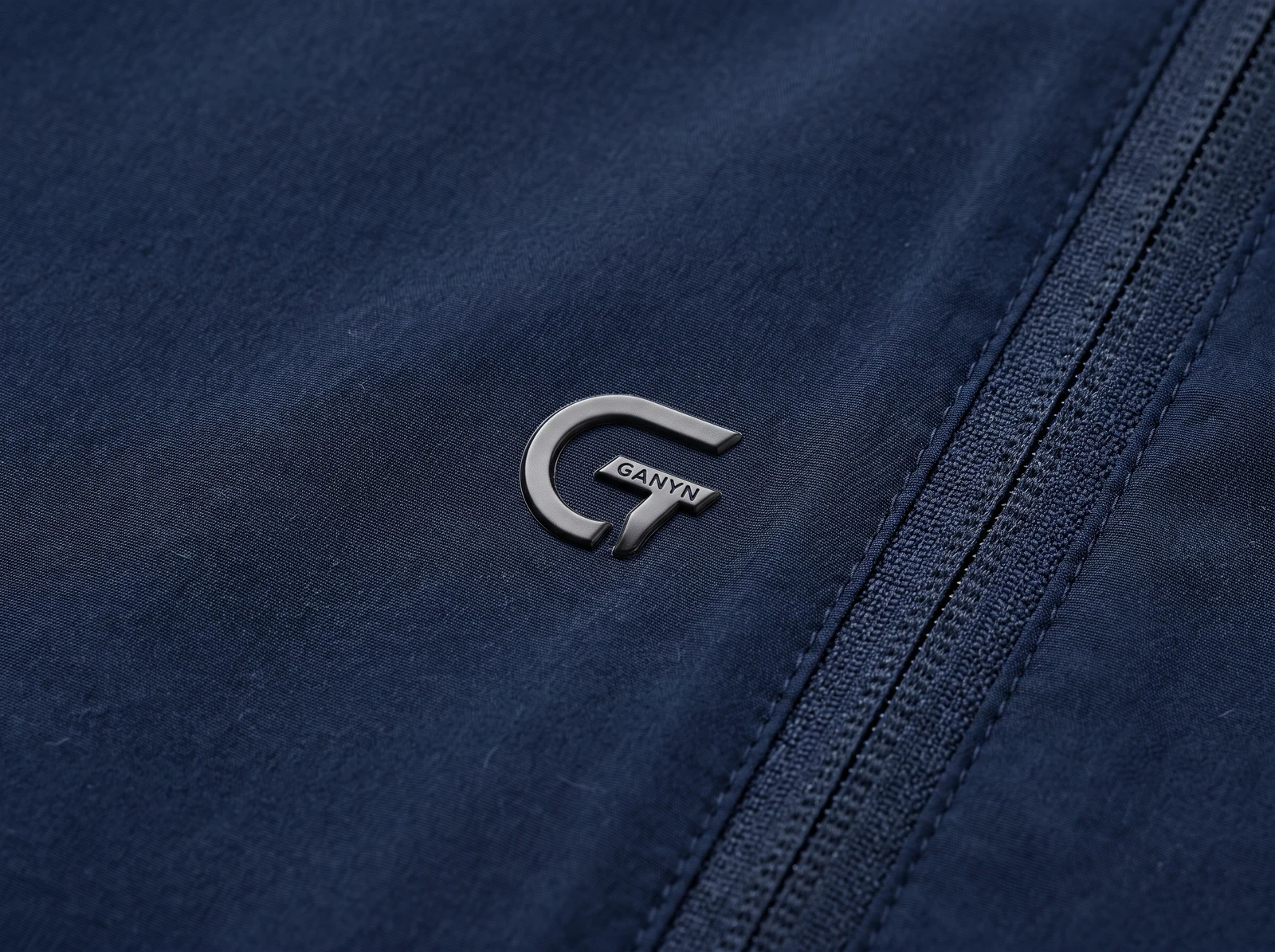 Dimensional silver-colored TPU mark applied to navy golf apparel